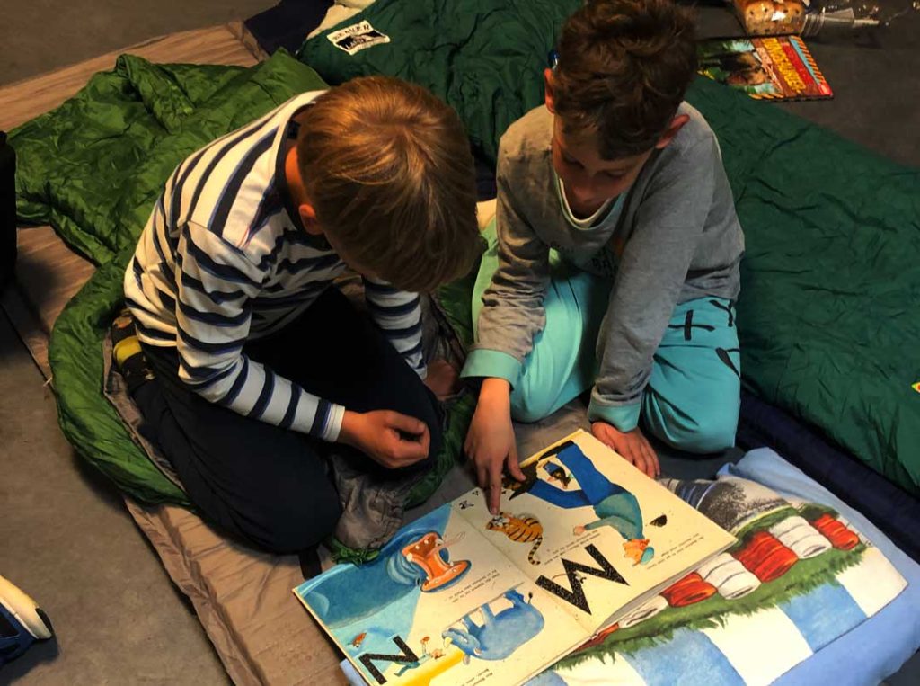 Kinder lesen mit Taschenlampen bei der Lesenacht der FES Grundschule.