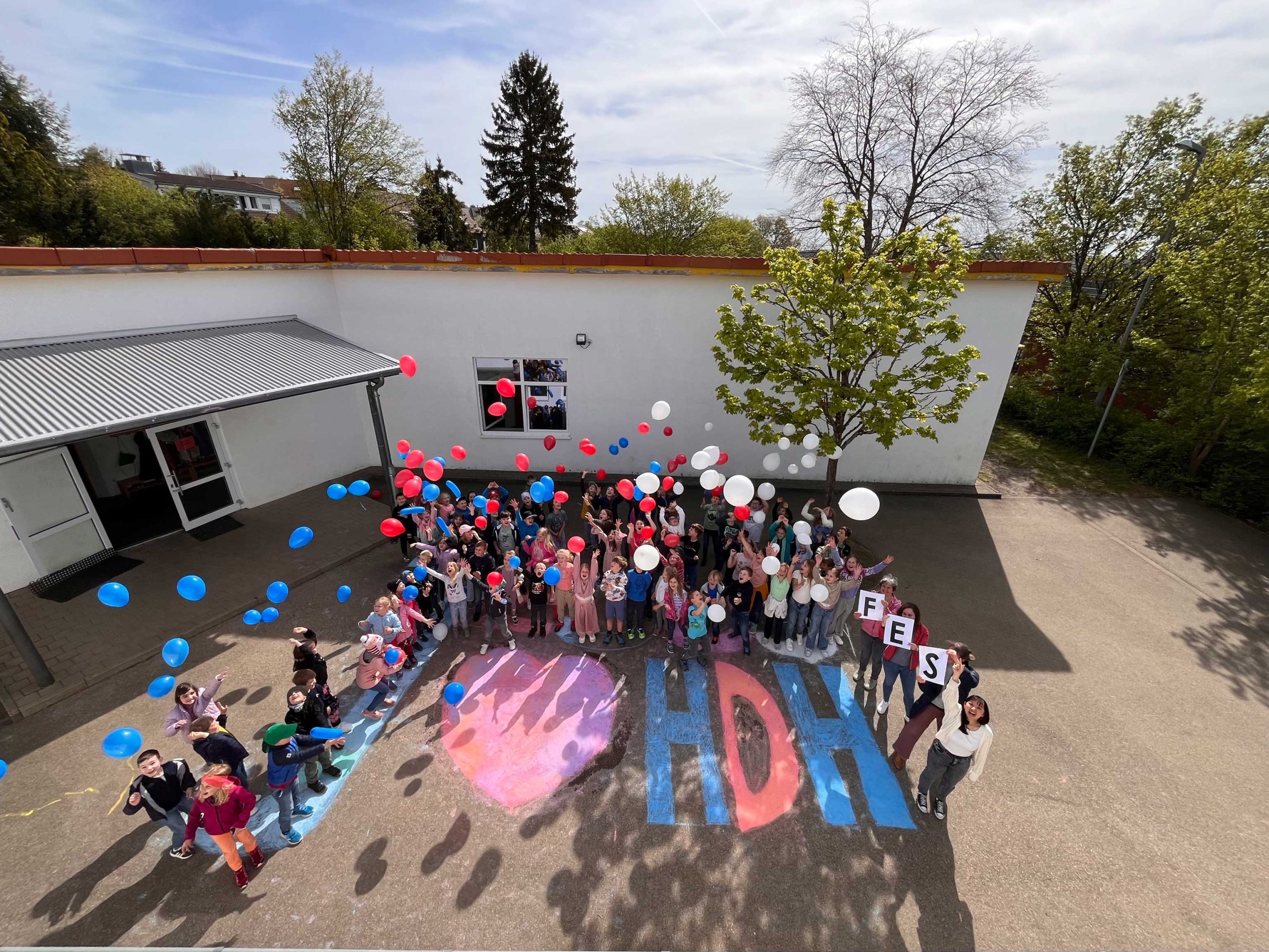 Luftaufnahme der Schülerinnen und Schüler der FES Grundschule Heidenheim auf ihrem Schulhof mit Ballons