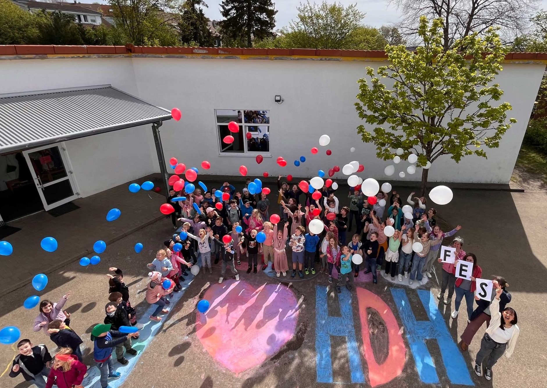 Luftaufnahme der Schülerinnen und Schüler der FES Grundschule Heidenheim auf ihrem Schulhof mit Ballons